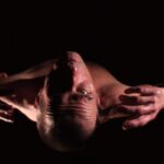 Video Still from "Shoe Test 2", showing George Saxon from above, looking into the camera.