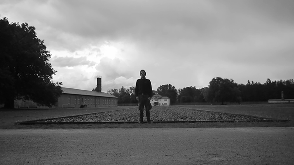Black and white photograph of George Saxon, standing on the cobble stones that are indicating the location of a former barrack.