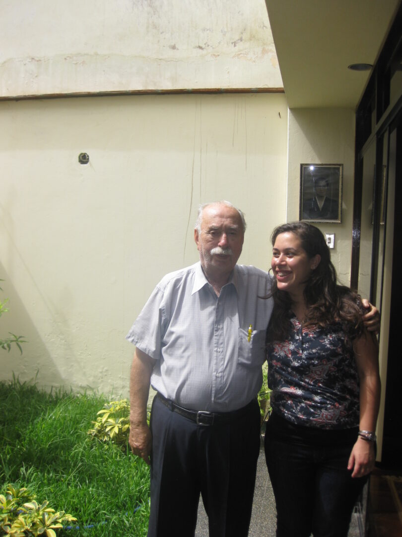 Danielle with her grandfather Hirsz Litmanovitz. They are standing in front of a house. Hirsz puts his arm around Danielle's shoulder.
